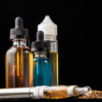 E-liquid bottles and e-cigarette with pile of grinded tobacco le