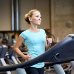 smiling woman exercising on treadmill in gym
