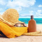 10001330 – suntan lotion, straw hat with towel at the beach
