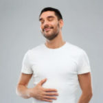 happy full man touching tummy over gray background