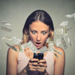 Shocked woman using smartphone dollar bills flying away from screen