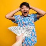 Surprised happy asian man receiving money banknotes