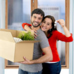 happy couple moving together in a new house unpacking cardboard boxes