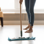 Closeup image barefoot girl doing house cleaning using wet mop