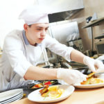 male cook chef decorating food on the plate