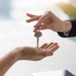Female hand giving keys to male client, buying renting apartment