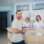 Male patient with doctor and nurse at reception desk in hospital