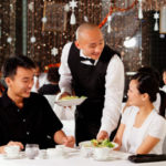Waiter serving couple at restaurant