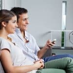 Man holding remote control while sitting with girlfriend at home