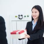 Beautiful young asian businesswoman giving christmas gift to her boss in office